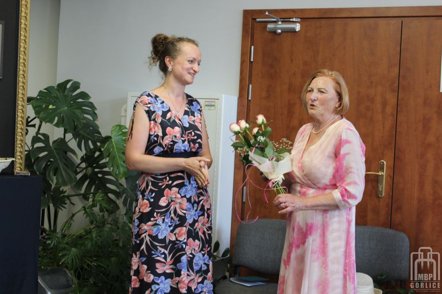 Teresa Pyka wręcza dziękuje i wręcza kwiaty dyrektorce biblioteki