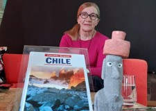 Powiększ zdjęcie Maria Zielińska na scenie pozuje z pamiątką — figurką małego Moai i przewodnikiem po Chile