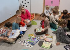 Powiększ zdjęcie Bibliotekarka prezentuje książkę popularnonaukową