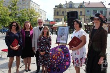 grupa osób pozuje do zdjecia w tle kapelusz oraz plakat z Narodowego Czytania