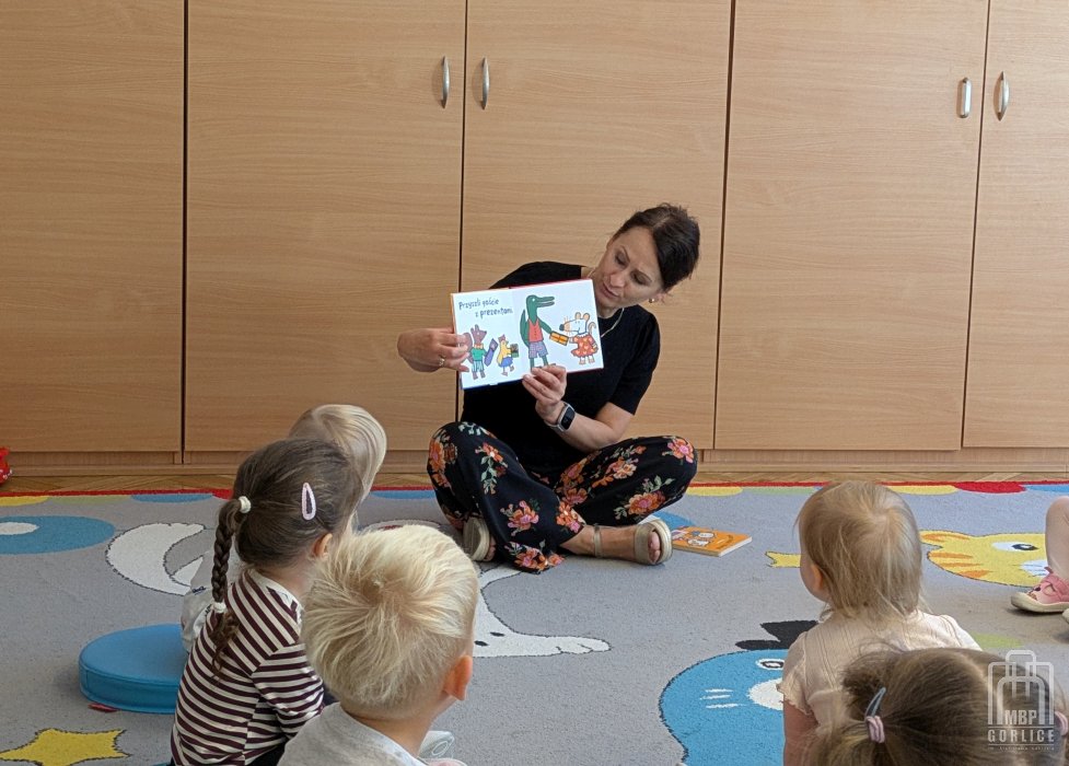 Biblioteka Gorlice, bibliotekarka czyta dzieciom książkę