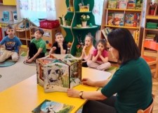 Powiększ zdjęcie Bibliotekarka czyta dzieciom książkę o Muminkach