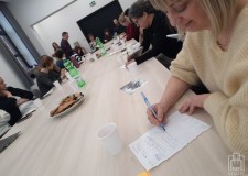 Przejdź do - Uśmiechnięta%20bibliotekarka%20siedzi%20przy%20stole%20i%20pisze%20na%20kartce,%20w%20tle%20inni%20uczestnicy%20szkolenia